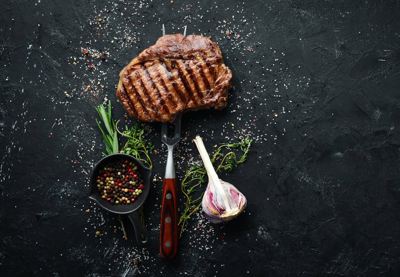 Gegrilltes Ribeye-Rindersteak auf der Gabel. Am gealterten Tisch. Oben vi