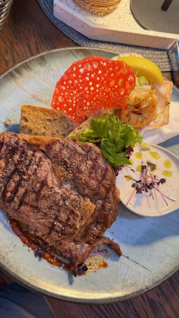 Ein gegrilltes Steak mit Brot, Salatgarnitur, rotem Chip und cremiger Soße auf Teller