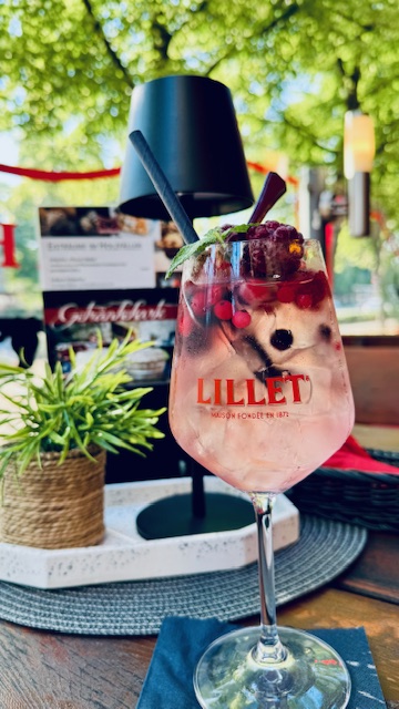 Ein erfrischender Lillet Cocktail mit Beeren und Minze in einem hellen Glas