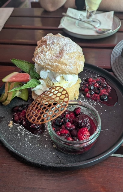 Eine kunstvoll angerichtete Nachspeise mit Sahne, Beeren und frischer Minze